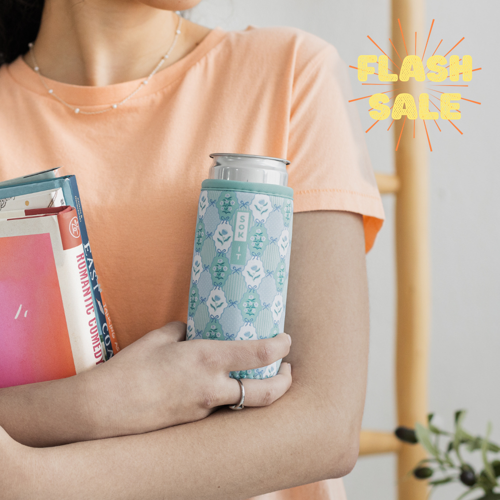 Person holding a can with a patterned sleeve and a book.