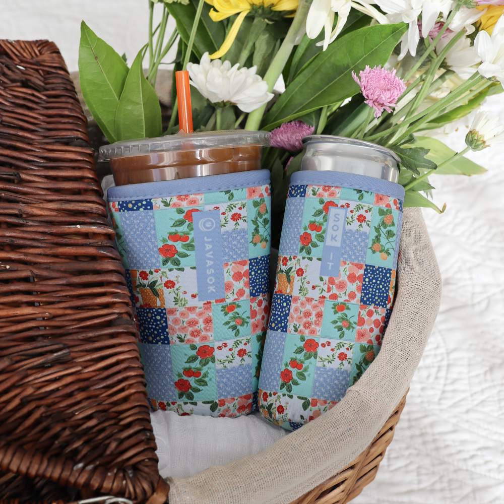 iced coffee and slim canned beverage in a basket with matching blue floral patchwork quilt neoprene drink sleeves